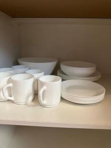 a shelf with white cups and plates on it at Уютная квартира in Almaty