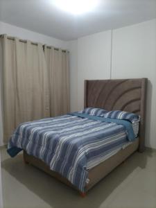 een bed met een blauwe en witte gestreepte deken erop bij Apartamento Meta Home zona exclusiva in Piura