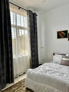 a bedroom with a bed and a large window at Lomes cozy home in Dar es Salaam