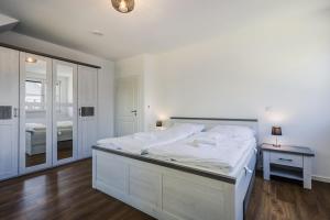 a white bedroom with a large bed and a mirror at Ferienhäuser Baltic Lagoon Haus 14 in Fuhlendorf
