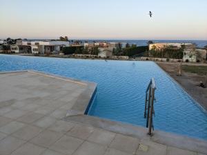 a large swimming pool with a view of the ocean at Sea & Golf Views 2BR Villa with Free Beach & Pool Access in Hurghada