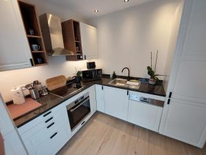 uma cozinha com armários brancos e um balcão preto em Viator Holidayhome em Tongeren