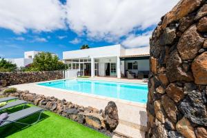 une maison avec une piscine et un mur en pierre dans l'établissement Casa YUKKA villa with heated pool, à Lajares