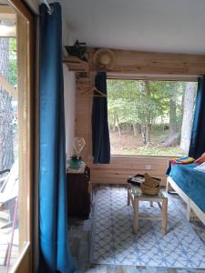 a room with a window and a bed and a table at Chalet Hibou Domaine de la Mamounette in Champclause
