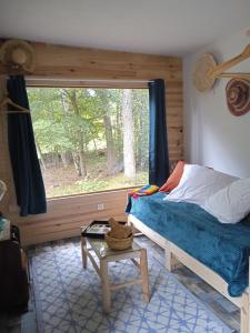 a bedroom with a bed and a window and a table at Chalet Hibou Domaine de la Mamounette in Champclause