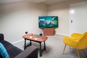 un soggiorno con divano, tavolo e TV di Albert Road Apartments Flat 3 a Colne