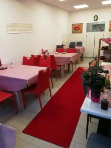 un comedor con mesas, sillas rojas y esterillas rojas en Gaestehaus jagsttalblick, en Langenburg
