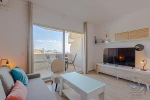 sala de estar con sofá, TV y mesa en Benal beach suite, parque acuático y vistas al mar, en Benalmádena