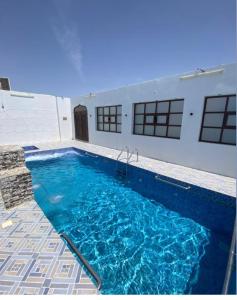 a swimming pool with blue water in front of a building at أستراحة السعادة in Jalan Bani Buhassan