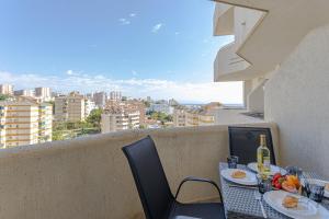 una mesa con platos de comida y vino en el balcón en Benal beach suite, parque acuático y vistas al mar, en Benalmádena