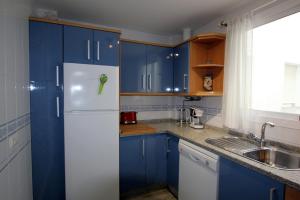 cocina con armarios azules y nevera blanca en Sanlúcar Apart Airen!!, en Sanlúcar de Barrameda