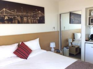 a hotel room with a bed, desk and a painting on the wall at PA Apartments in Brisbane