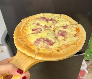a person holding a pizza on a wooden paddle at Fancy Hostel and Bar in Ha Long +24 photos