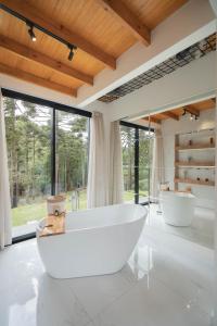 uma casa de banho com 2 banheiras brancas e janelas grandes em Morada Reino Encantado em São Joaquim