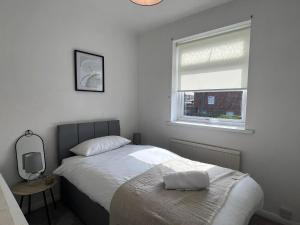 um quarto branco com uma cama e uma janela em Alexander Apartments Marsden em South Shields