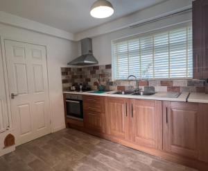 uma cozinha com armários de madeira, um lavatório e uma janela em Alexander Apartments Marsden em South Shields