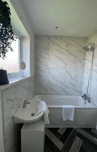 Baño blanco con bañera y lavamanos en Alexander Apartments Marsden en South Shields