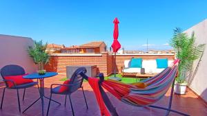 d'une terrasse avec un hamac, une table et des chaises. dans l'établissement Ático Deluxe Granada, Parking gratis y Terraza, à Armilla