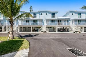 a large white building with a palm tree in front of it at Ocean Isles #119 in Marathon