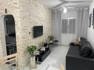 a living room with a black couch and a brick wall at Charmoso apartamento 01 Quarto Enseada in Guarujá