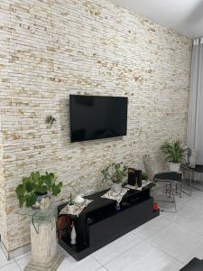 a living room with a brick wall with a tv on it at Charmoso apartamento 01 Quarto Enseada in Guarujá