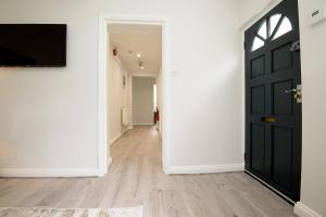 an empty hallway with a black door and wooden floors at K Suites - Kauto Star Suite in Cheltenham