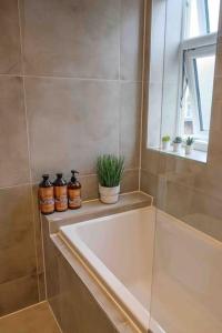 ein Badezimmer mit einer Badewanne, einem Fenster und Topfpflanzen in der Unterkunft Garden of Eden 1 Bedroom Flat in Fishponds in Bristol