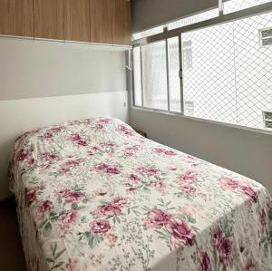 1 dormitorio con 1 cama con colcha de flores en A tranquilidade está a seu alcance., en São Vicente