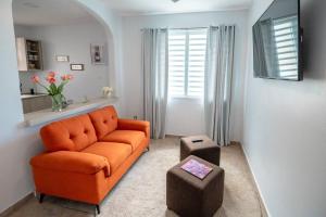 sala de estar con sofá naranja y 2 taburetes en 1 Santurce 1 Bedroom 1Bathroom Apt en San Juan