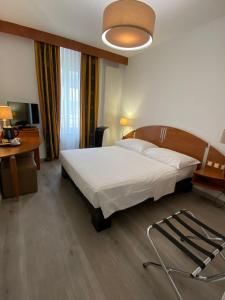 um quarto com uma cama, uma mesa e um candeeiro em Hotel Admiral em Genebra