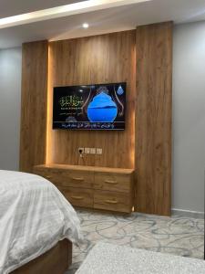 a bedroom with a tv on a wooden wall at درة اجنادين للشقق المخدومة in Tabuk