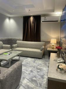 a living room with two couches and a table at درة اجنادين للشقق المخدومة in Tabuk