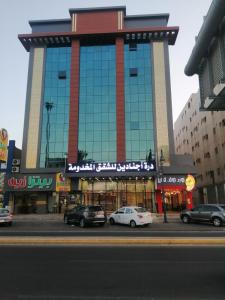 un gran edificio con coches estacionados frente a él en درة اجنادين للشقق المخدومة, en Tabuk