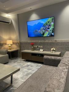 uma sala de estar com um sofá e uma televisão na parede em درة اجنادين للشقق المخدومة em Tabuk