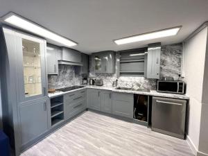 a large kitchen with gray cabinets and appliances at Langley Bungalow in Slough
