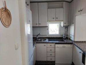 a kitchen with white cabinets and a sink and a window at Primera línea de Playa in Almuñécar