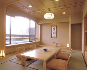 Pokój ze stołem i krzesłami oraz dużym oknem w obiekcie Maruei w mieście Fujikawaguchiko