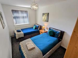 a bedroom with two blue beds and a window at K Suites - Harrogate Terrace in Bradford