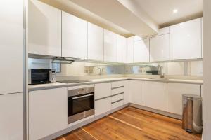 a white kitchen with white cabinets and a wooden floor at Luxury 2 bedroom flat in Holborn in London