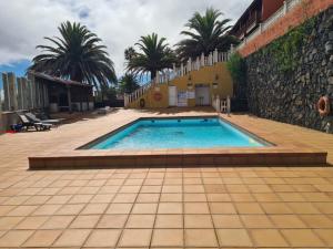 a swimming pool next to a building with palm trees at Lourdes 1 casa compartida solo con la anfitriona in Breña Baja