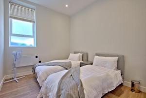 two beds in a white room with a window at K Suites - Westborough Road in Southend-on-Sea