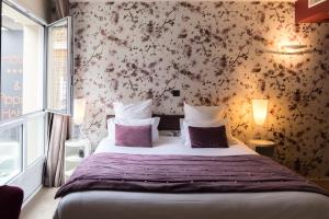 sypialnia z dużym łóżkiem z kwiatami na ścianie w obiekcie Hôtel L'Adresse w Saint-Malo