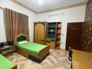 a bedroom with a green bed and a cabinet at Bright And Vintage 3 BR Suite in Cairo