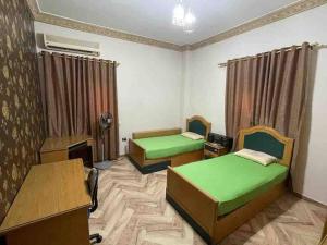 Cette chambre comprend deux lits, un bureau et une table. dans l'établissement Bright And Vintage 3 BR Suite, au Caire