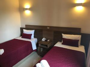 2 Betten in einem Hotelzimmer mit roter und weißer Bettwäsche in der Unterkunft Ipe Center Hotel in Sao Jose do Rio Preto