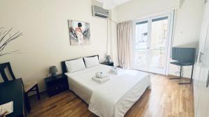 um quarto com uma cama branca e uma televisão em Harokopio Apartment in Athens em Atenas