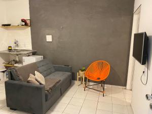 Flat próximo ao Centro de CG com Wifi rápida في كامبينا غراندي: غرفة معيشة مع أريكة وكرسي برتقالي