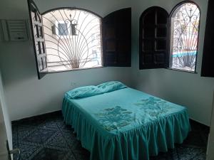 uma cama num quarto com duas janelas em Casa grande em área central, bem iluminada e vent. em Manaus