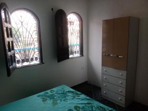 um quarto com 2 janelas, uma cama e uma cómoda em Casa grande em área central, bem iluminada e vent. em Manaus