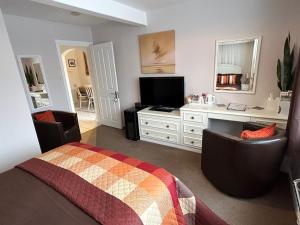 Puck's Retreat Bed & Breakfast في Tredington: غرفة نوم بسرير ومكتب وتلفزيون